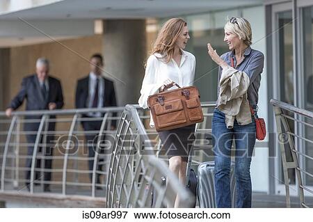Male and female business team walking and talking leaving hotel View Large Photo Image Stock Photo - Male and female business team walking and talking leaving hotel. Fotosearch