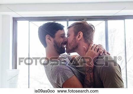 Picture - Male couple at home, fooling around, kissing and laughing. Fotosearch