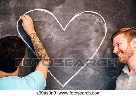 Male couple drawing heart on blackboard View Large Photo Image Stock Photo - Male couple drawing heart on blackboard. Fotosearch