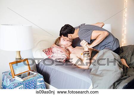 Male couple on bed, holding hands, kissing View Large Photo Image Stock Image - Male couple on bed, holding hands, kissing. Fotosearch