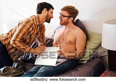 Male couple on bed, young man trying to close his partner's laptop View Large Photo Image Stock Photo - Male couple on bed, young man trying to close his partner's laptop. Fotosearch