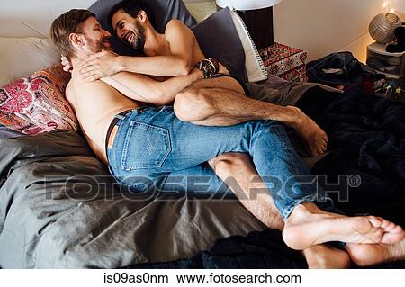 Male couple, partially dressed, lying on bed, embracing View Large Photo Image Picture - Male couple, partially dressed, lying on bed, embracing. Fotosearch