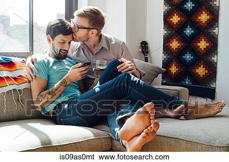 Stock Photograph - Male couple relaxing on sofa together. Fotosearch