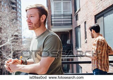 Male couple standing on balcony, standing away from each other, with sad expression View Large Photo Image Stock Image - Male couple standing on balcony, standing away from each other, with sad expression. Fotosearch