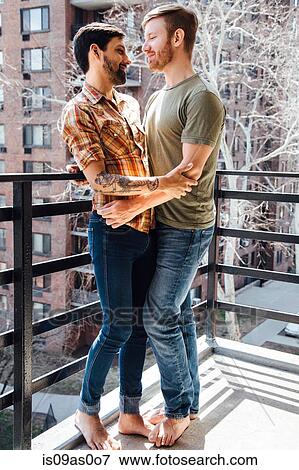 Male couple standing on balcony, embracing, face to face View Large Photo Image Stock Photo - Male couple standing on balcony, embracing, face to face. Fotosearch