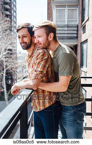 Male couple standing on balcony, looking at view, embracing View Large Photo Image Stock Photography - Male couple standing on balcony, looking at view, embracing. Fotosearch
