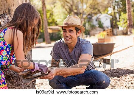 Mid adult man in community garden handing tree bark to daughter View Large Photo Image Stock Image - Mid adult man in community garden handing tree bark to daughter. Fotosearch