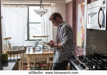 Mid adult man in kitchen using touchscreen on digital tablet View Large Photo Image Stock Photography - Mid adult man in kitchen using touchscreen on digital tablet. Fotosearch