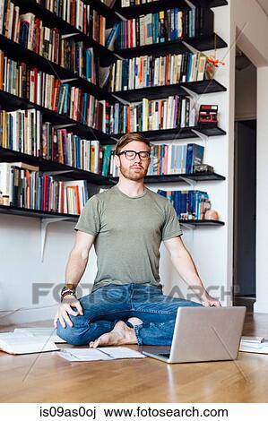 Mid adult man sitting in front of laptop in yoga position View Large Photo Image Stock Image - Mid adult man sitting in front of laptop in yoga position. Fotosearch