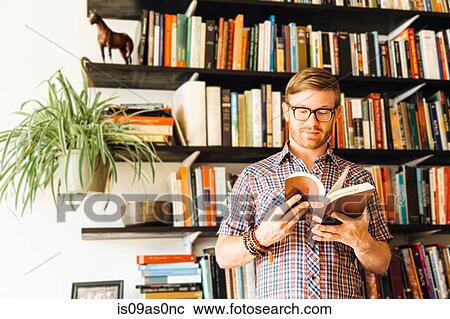 Mid adult man, standing in front of bookshelf, reading View Large Photo Image Stock Image - Mid adult man, standing in front of bookshelf, reading. Fotosearch