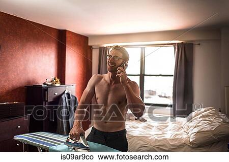 Mid adult man wearing boxer shorts chatting on smartphone whilst ironing View Large Photo Image Picture - Mid adult man wearing boxer shorts chatting on smartphone whilst ironing. Fotosearch