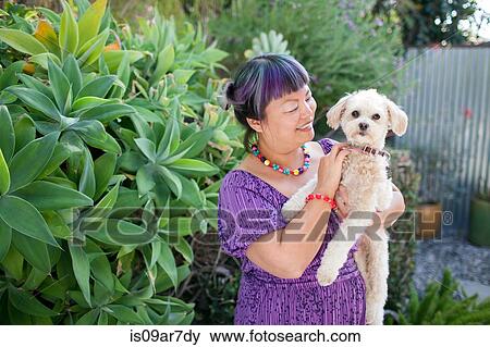 Stock Photo - Mid adult woman outdoors, holding dog. Fotosearch