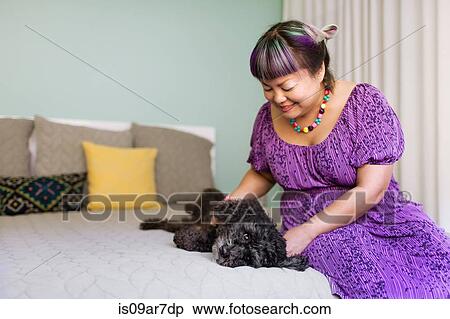 Stock Photography - Mid adult woman stroking dog. Fotosearch