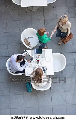 Overhead view of businesswomen shaking hands on hotel terrace View Large Photo Image Stock Photo - Overhead view of businesswomen shaking hands on hotel terrace. Fotosearch