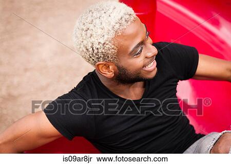Stock Photography - Portrait of a young man with bleached hair, smiling. Fotosearch
