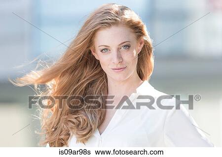 Stock Photograph - Portrait of beautiful young woman with long red flyaway hair. Fotosearch