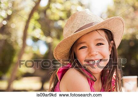 Stock Image - Portrait of cute smiling girl wearing straw hat. Fotosearch