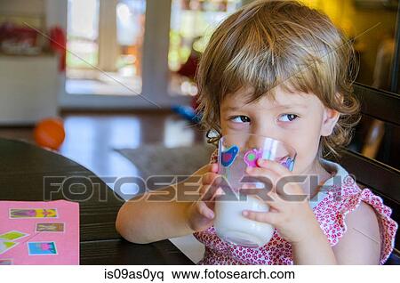 Portrait of cute young girl drinking glass of milk at kitchen table View Large Photo Image Stock Photography - Portrait of cute young girl drinking glass of milk at kitchen table. Fotosearch