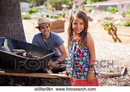 Picture - Portrait of girl in community garden with father and wheelbarrow. Fotosearch