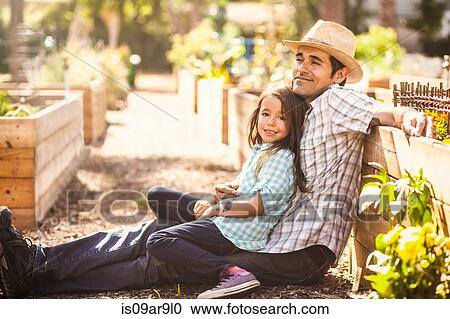 Portrait of girl in community garden sitting on fathers knee View Large Photo Image Stock Image - Portrait of girl in community garden sitting on fathers knee. Fotosearch