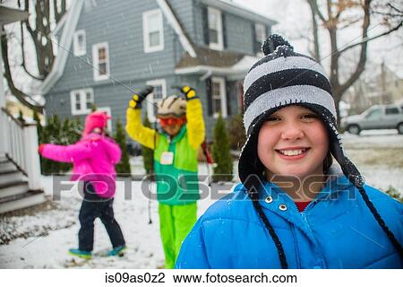 Stock Image - Portrait of girl wearing black and white striped hat in snowy garden. Fotosearch