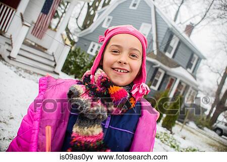 Stock Photo - Portrait of girl wearing pink hat in snowy garden. Fotosearch