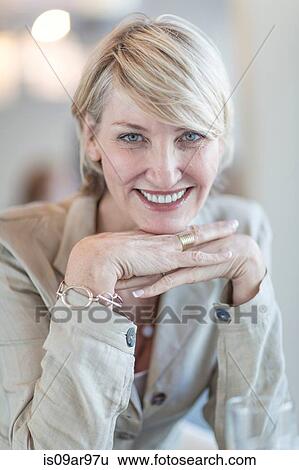 Stock Photograph - Portrait of mature businesswoman with chin on hands. Fotosearch