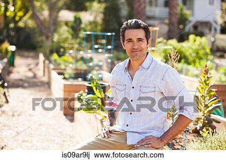 Portrait of mid adult man sitting in community garden View Large Photo Image Stock Image - Portrait of mid adult man sitting in community garden. Fotosearch