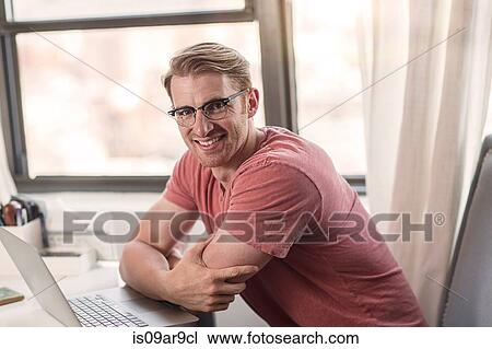 Stock Image - Portrait of mid adult man using laptop. Fotosearch