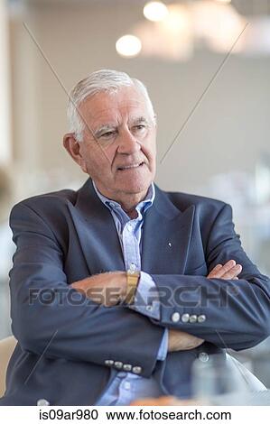 Stock Image - Portrait of senior businessman at breakfast in hotel restaurant. Fotosearch