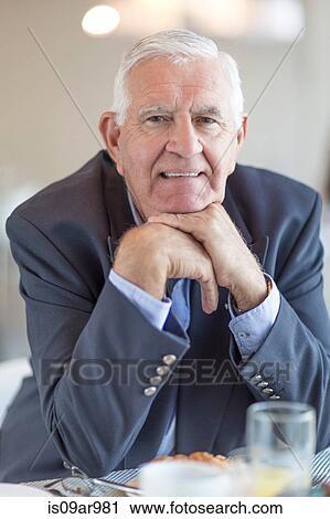 Stock Image - Portrait of senior businessman having breakfast in hotel restaurant. Fotosearch