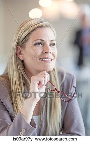 Portrait of smiling mid adult businesswoman holding spectacles View Large Photo Image Stock Photo - Portrait of smiling mid adult businesswoman holding spectacles. Fotosearch