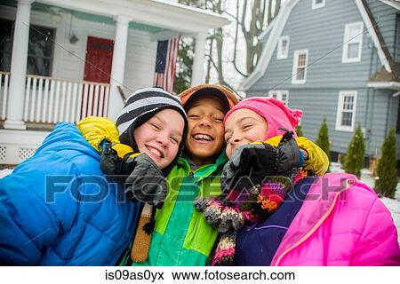 Stock Photo - Portrait of two girls and boy wearing knitted hats in snowy garden. Fotosearch