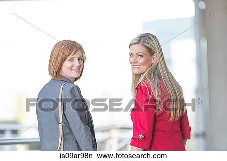 Portrait of two women friends looking over their shoulders in city View Large Photo Image Picture - Portrait of two women friends looking over their shoulders in city. Fotosearch