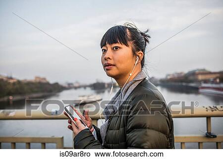 Portrait of woman in front of river wearing earphones View Large Photo Image Picture - Portrait of woman in front of river wearing earphones. Fotosearch