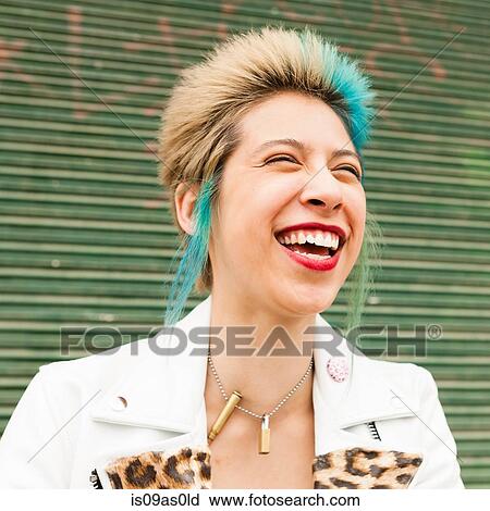 Stock Image - Portrait of young woman with colourful hair, laughing, outdoors. Fotosearch
