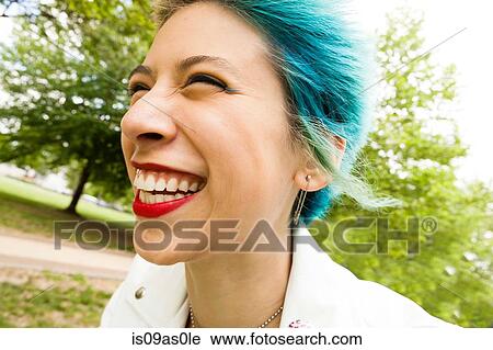 Stock Image - Portrait of young woman with colourful hair, laughing, outdoors. Fotosearch