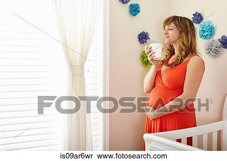 Pregnant woman drinking coffee and daydreaming in nursery View Large Photo Image Stock Photography - Pregnant woman drinking coffee and daydreaming in nursery. Fotosearch