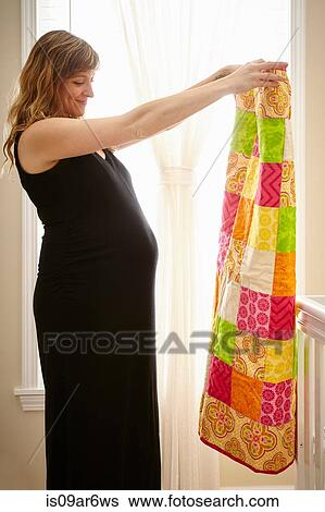 Pregnant woman holding up homemade quilt in nursery View Large Photo Image Stock Photograph - Pregnant woman holding up homemade quilt in nursery. Fotosearch