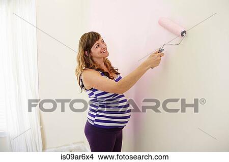 Pregnant woman painting nursery walls pink View Large Photo Image Picture - Pregnant woman painting nursery walls pink. Fotosearch