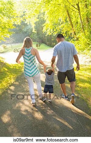 Rear view of couple holding hands and swinging toddler son in park View Large Photo Image Stock Photograph - Rear view of couple holding hands and swinging toddler son in park. Fotosearch
