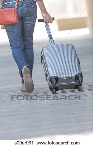 Rear waist down view of mature woman leaving hotel with wheeled suitcase View Large Photo Image Stock Image - Rear waist down view of mature woman leaving hotel with wheeled suitcase. Fotosearch