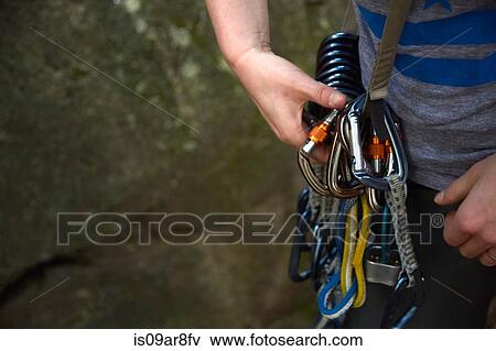 Stock Photo - Rock climber preparing safety harness. Fotosearch