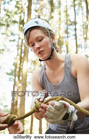 Stock Photo - Rock climber preparing safety harness. Fotosearch
