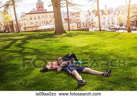 Picture - Romantic young sporty couple lying on grass in park. Fotosearch