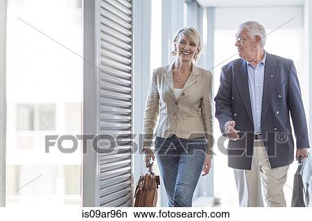 Senior businessman and woman walking in hotel corridor View Large Photo Image Picture - Senior businessman and woman walking in hotel corridor. Fotosearch