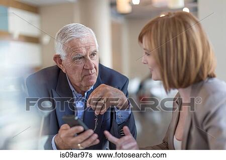 Senior businessman smartphone text to colleague at breakfast table in hotel restaurant View Large Photo Image Stock Photograph - Senior businessman smartphone text to colleague at breakfast table in hotel restaurant. Fotosearch