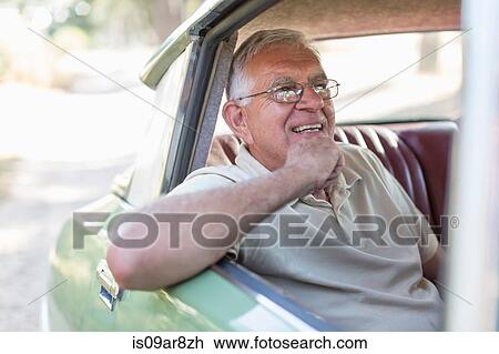 Stock Image - Senior man sitting in back seat of car, smiling. Fotosearch