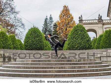Picture - Side view of woman on stone steps posing on one leg, Prague, Czech Republic. Fotosearch