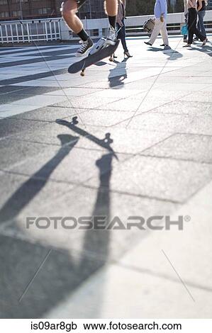 Stock Image - Skateboarder performing trick, low section. Fotosearch